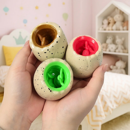 Three colorful ceramic eggs held in a hand with a soft, pastel-colored room in the background.