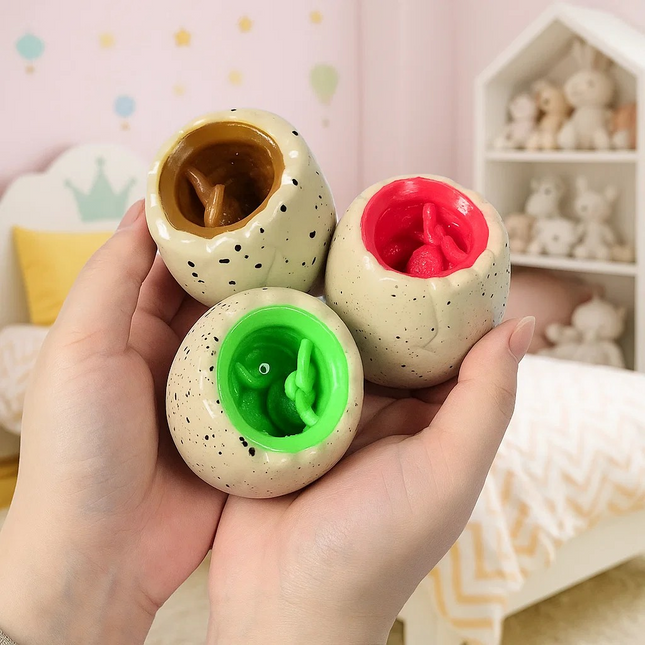 Three colorful ceramic eggs held in a hand with a soft, pastel-colored room in the background.