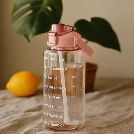 Clear water bottle with motivational phrases and pink lid on a neutral background