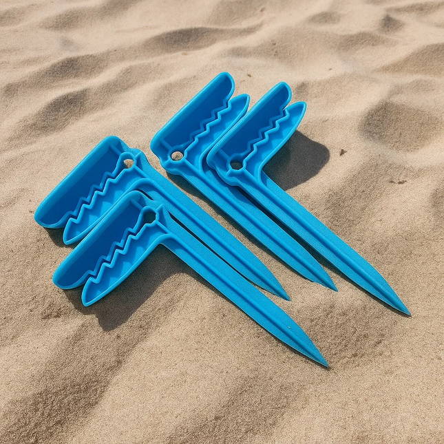 Four blue towel or picnic blanket stakes on sand