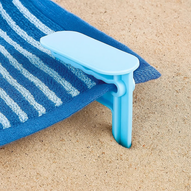 Blue sand anchor holding a blue towel on sand