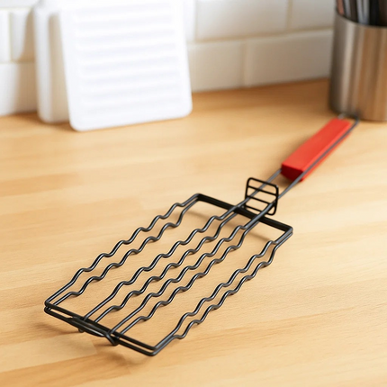 Black sausage wire rack on a wooden surface with a red handle
